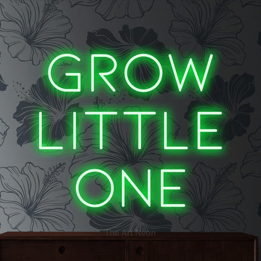 Green LED neon sign reading "Grow Little One" against grey floral wallpaper for nursery décor