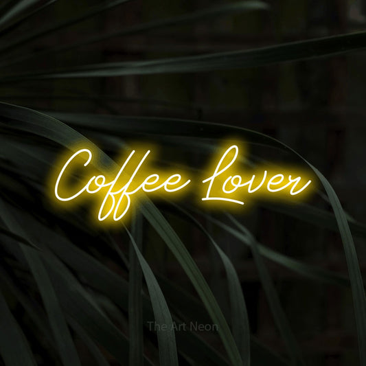 Yellow script-style LED neon sign reading "Coffee Lover" against dark tropical leaves for kitchen décor