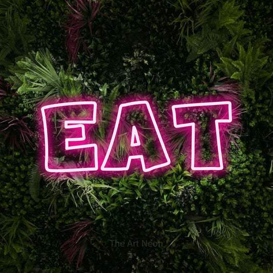 Hot pink outline-style LED neon sign reading "Eat" against a lush garden wall with pink flowers for kitchen décor