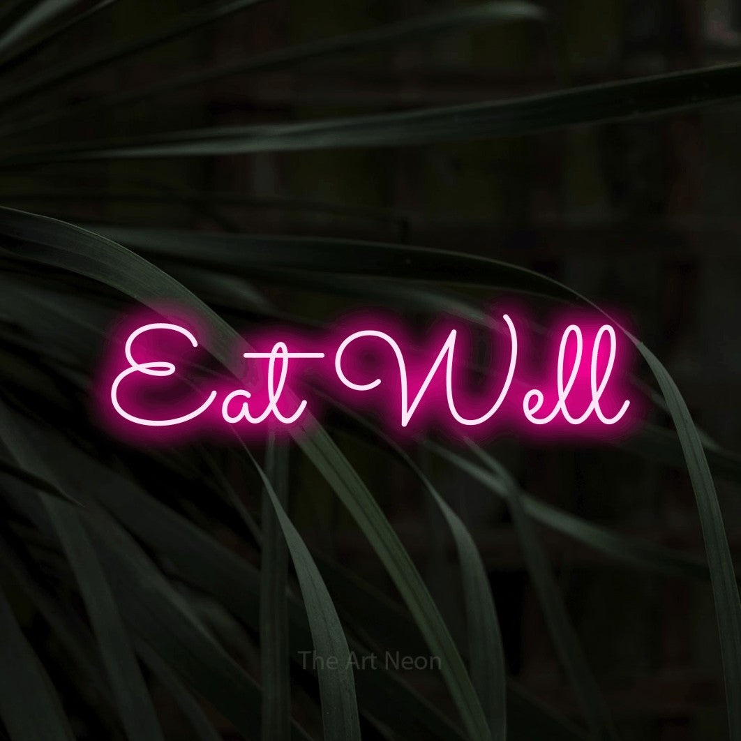 Enseigne néon à DEL à lumière rose vif, affichant « Eat Well » sur des feuilles tropicales foncées, pour décorer une cuisine