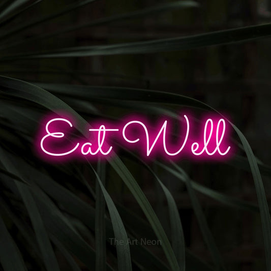 Hot pink LED neon sign reading "Eat Well" against dark tropical leaves for kitchen décor