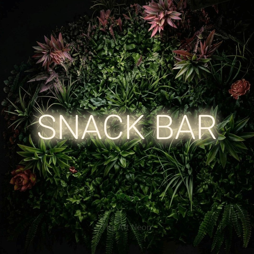 Warm white LED neon sign reading "Snack Bar" against a flowering garden wall for kitchen décor