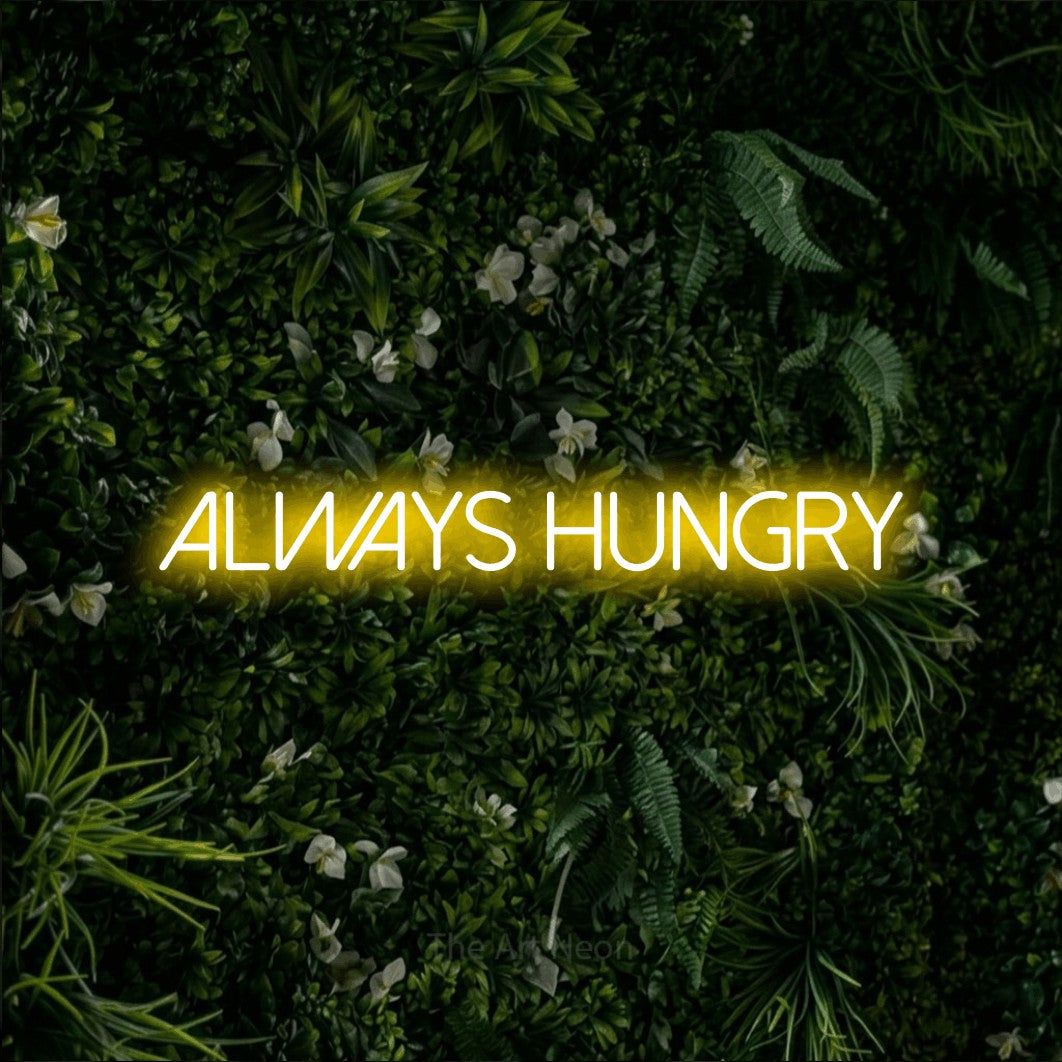 Yellow LED neon sign reading "Always Hungry" against a leafy green wall for kitchen décor