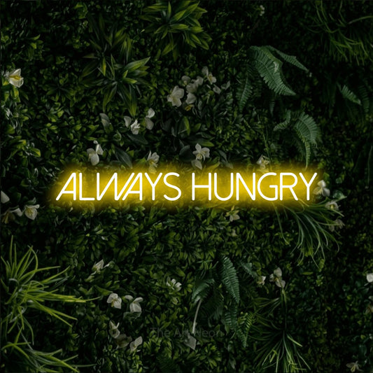 Yellow LED neon sign reading "Always Hungry" against a leafy green wall for kitchen décor