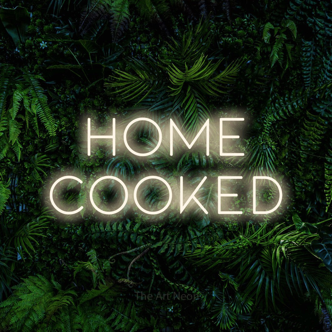 Warm white LED neon sign reading "Home Cooked" against a dense tropical foliage wall for kitchen décor