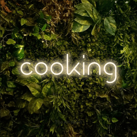Warm white LED neon sign reading "Cooking" against a textured moss and foliage wall for kitchen décor