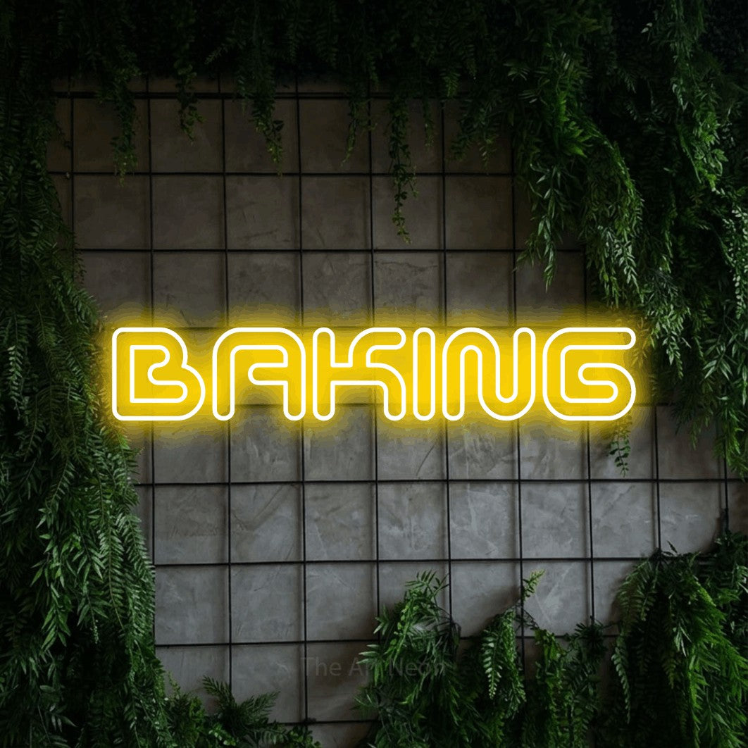 Yellow outline-style LED neon sign reading "Baking" against a green grid wall with foliage for kitchen décor
