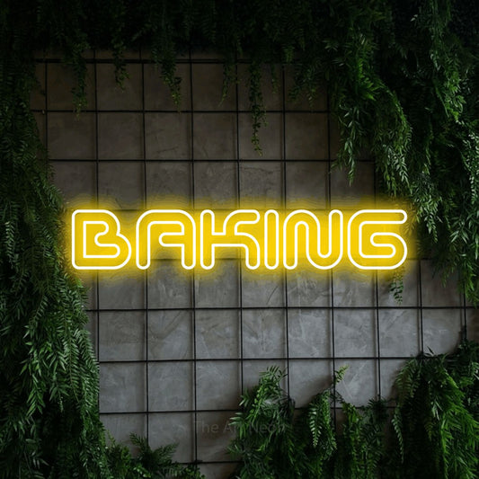 Yellow outline-style LED neon sign reading "Baking" against a green grid wall with foliage for kitchen décor