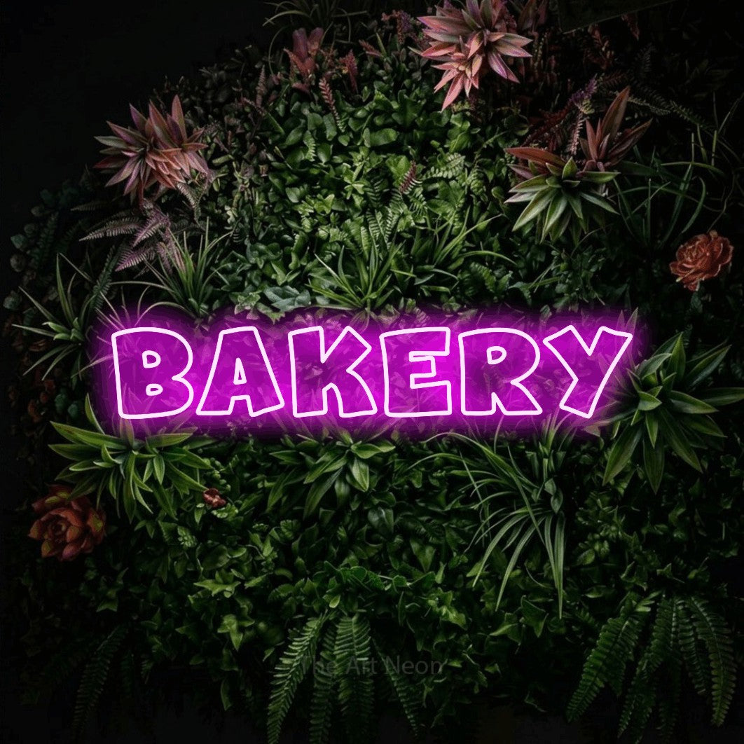 Pink outline-style LED neon sign reading "Bakery" against a flowering garden wall for kitchen décor