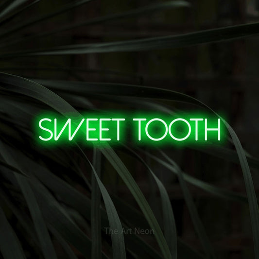 Green LED neon sign reading "Sweet Tooth" against dark tropical leaves for kitchen décor