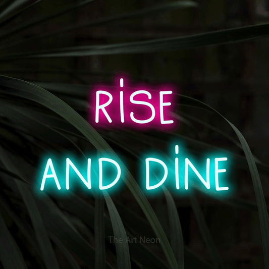 Ice blue and hot pink LED neon sign reading "Rise and Dine" against dark tropical leaves for kitchen décor