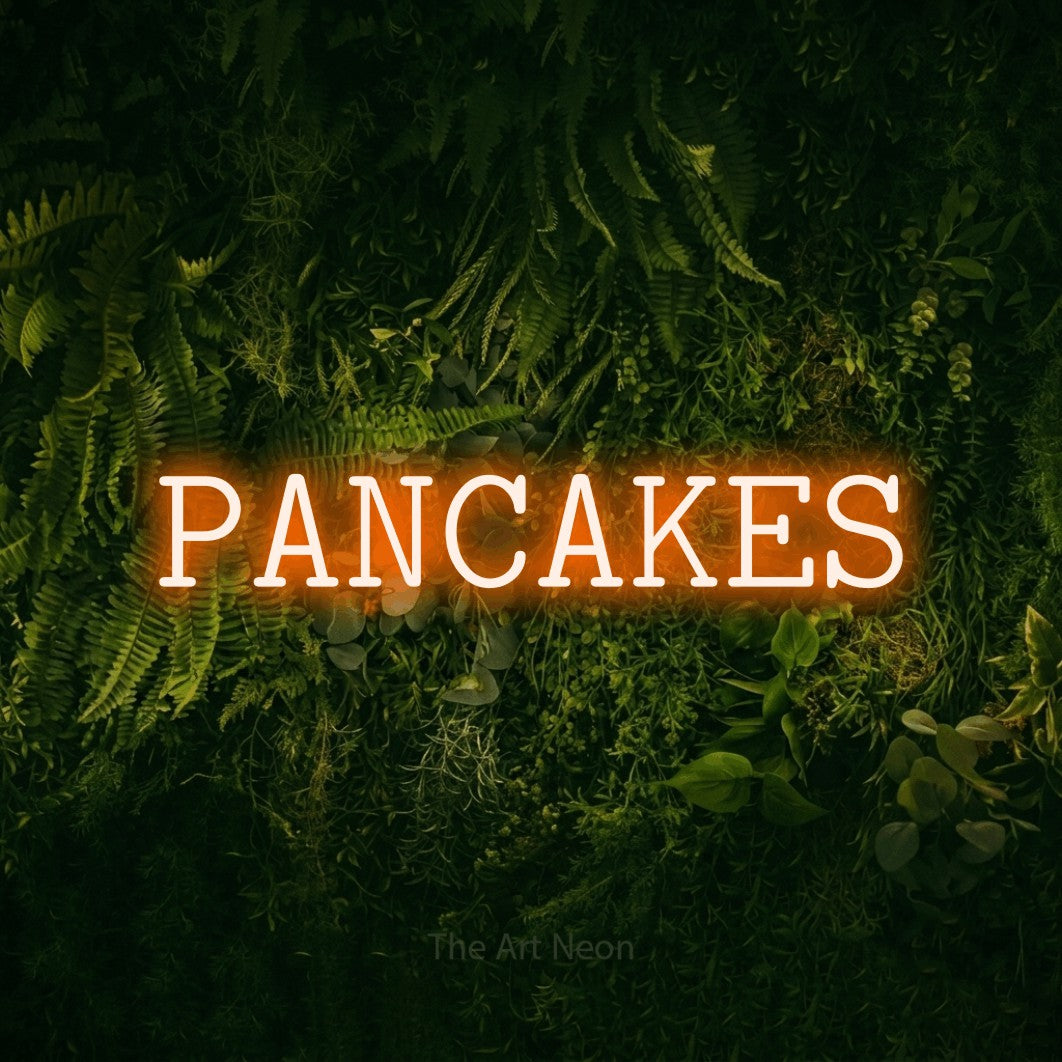 Orange LED neon sign reading "Pancakes" against a moss-covered green wall for kitchen décor