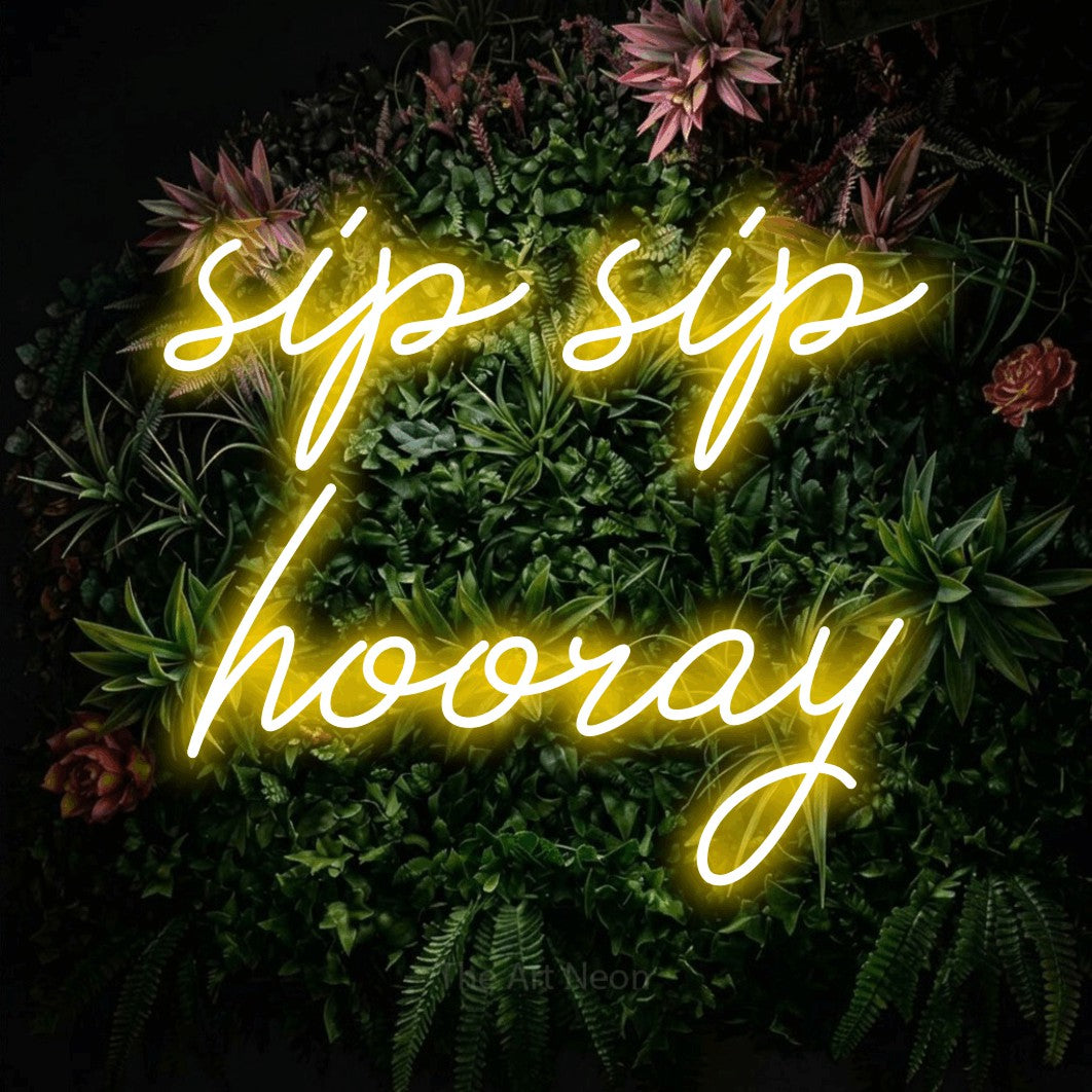 Yellow script-style LED neon sign reading "Sip Sip Hooray" against a flowering garden wall for kitchen décor