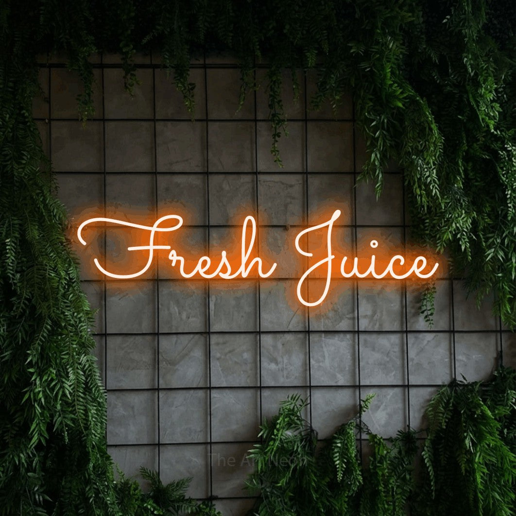 Orange LED neon sign reading "Fresh Juice" against a green grid wall with foliage for kitchen décor