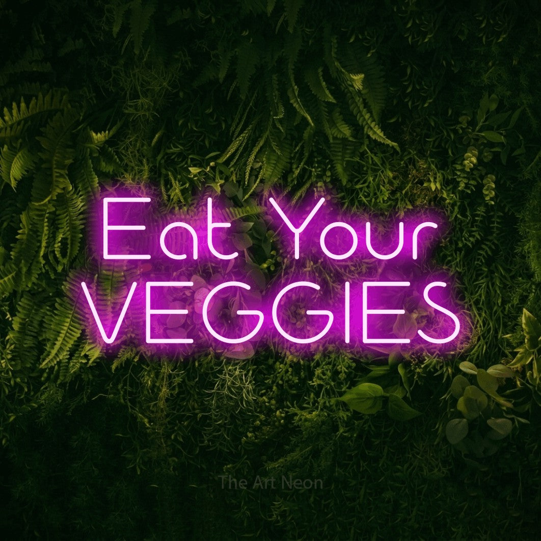Pink LED neon sign reading "Eat Your Veggies" against a moss-covered green wall for kitchen décor