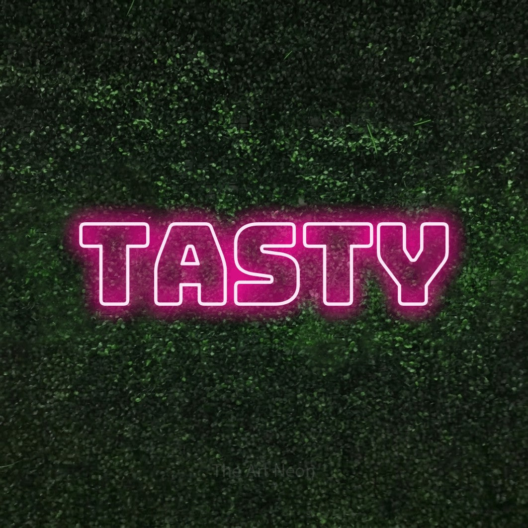 Hot pink outline-style LED neon sign reading "Tasty" against a textured green moss wall for kitchen décor