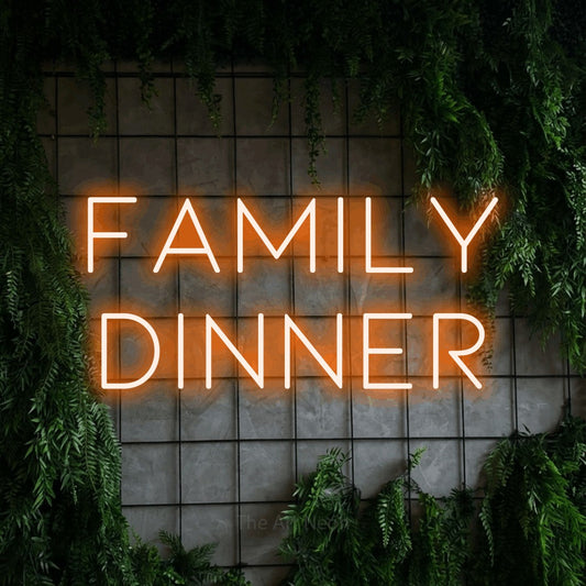 Orange LED neon sign reading "Family Dinner" against a green grid wall with foliage for kitchen décor