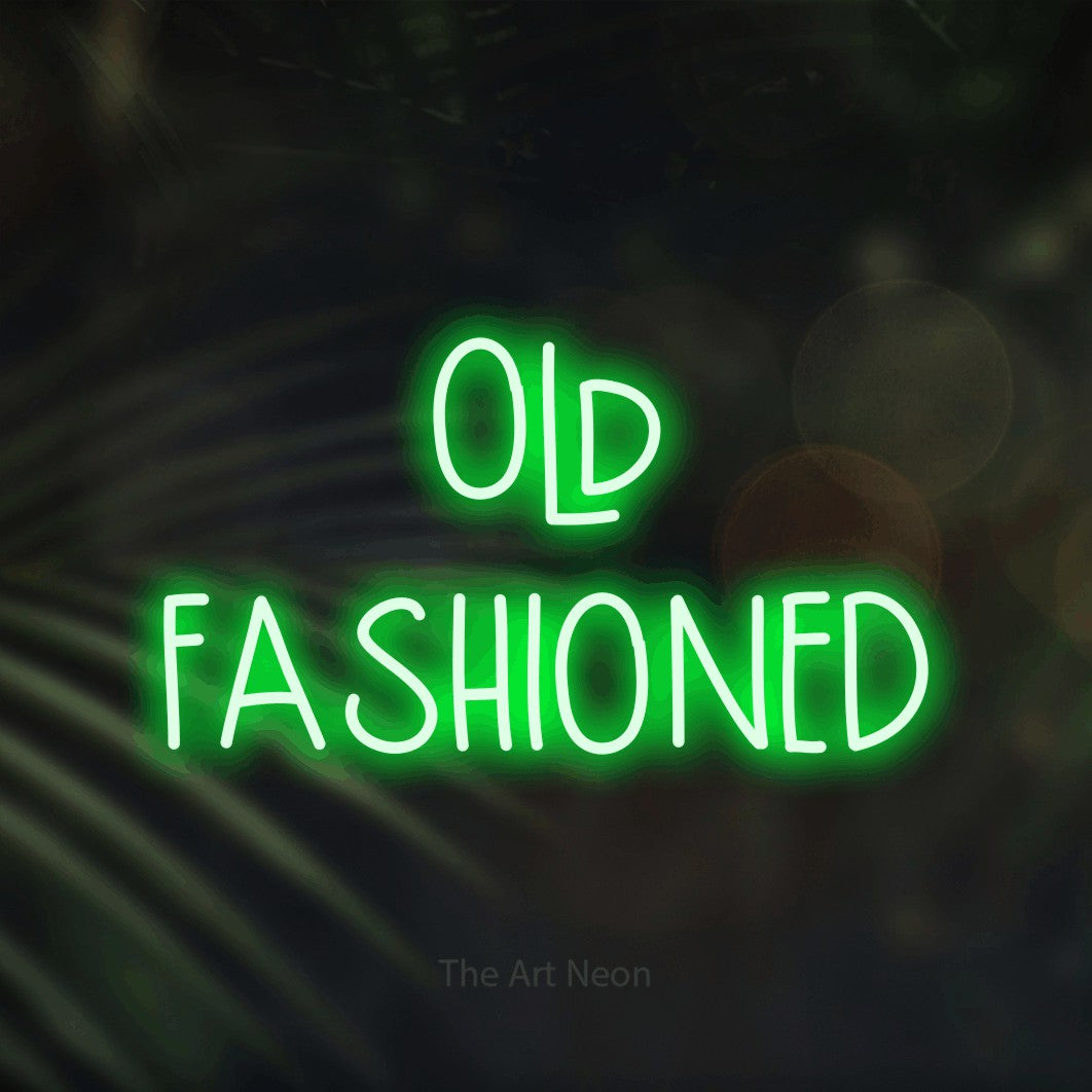 Green LED neon sign reading "Old Fashioned" against dark blurred palm leaves for bar décor