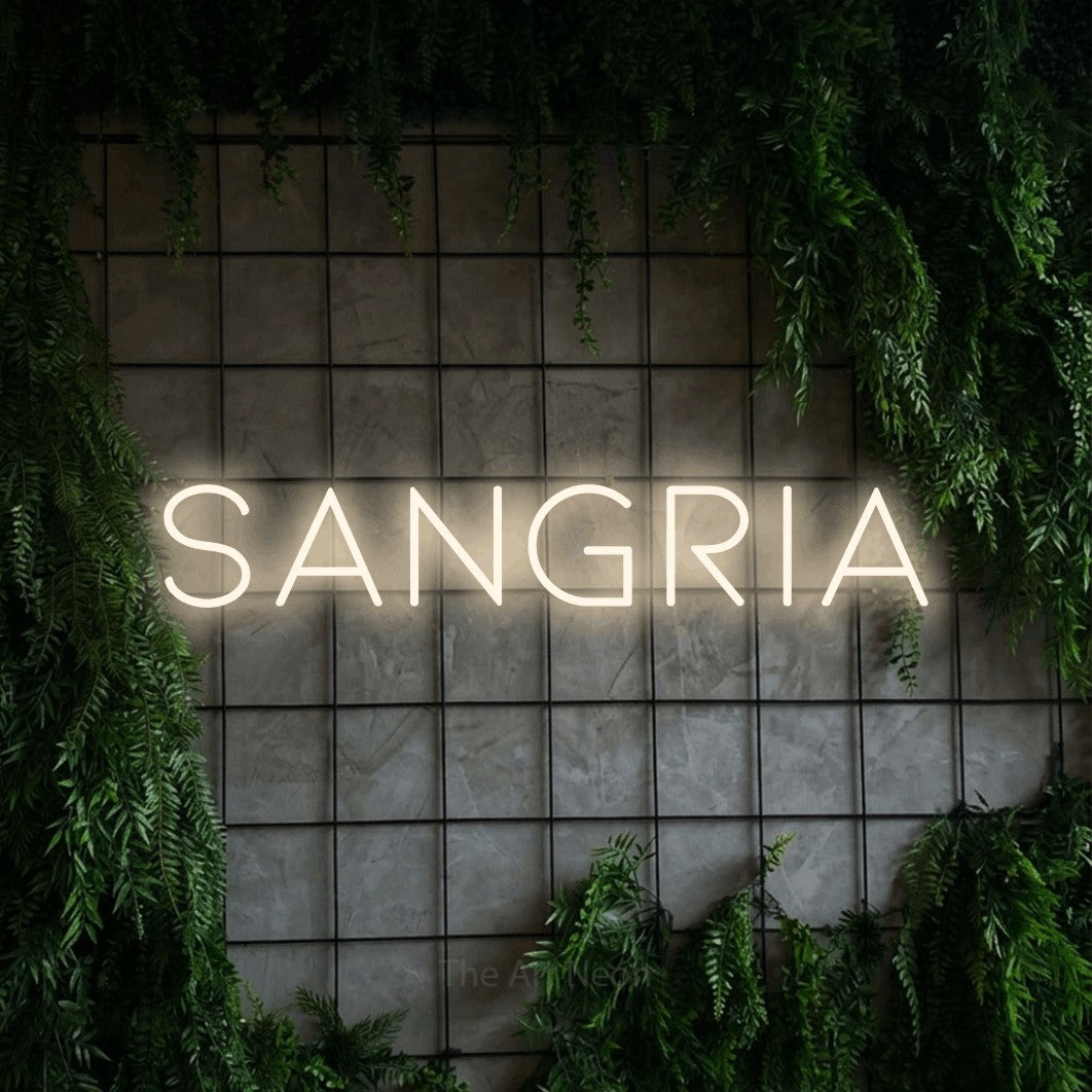 Warm white LED neon sign reading "Sangria" against a green grid wall with foliage for bar décor