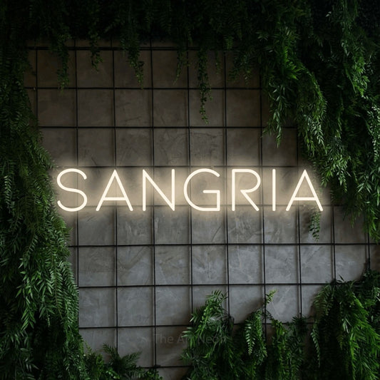 Warm white LED neon sign reading "Sangria" against a green grid wall with foliage for bar décor