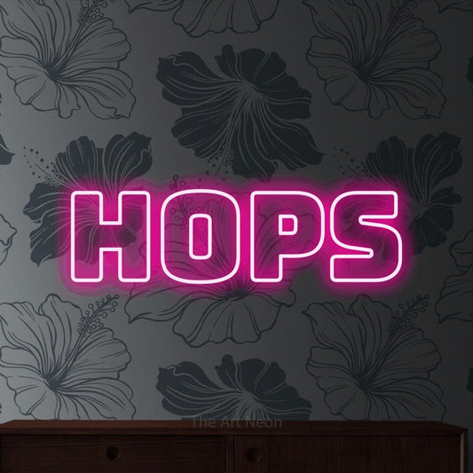 Hot pink outline-style LED neon sign reading "Hops" against grey floral wallpaper for bar décor