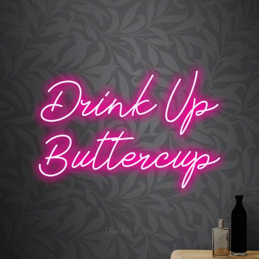 Hot pink script-style LED neon sign reading "Drink Up Buttercup" against light grey floral wallpaper for bar décor