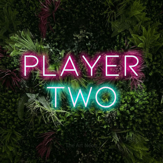 Ice blue and hot pink LED neon sign reading "Player Two" against a lush garden wall with pink flowers for gaming room décor