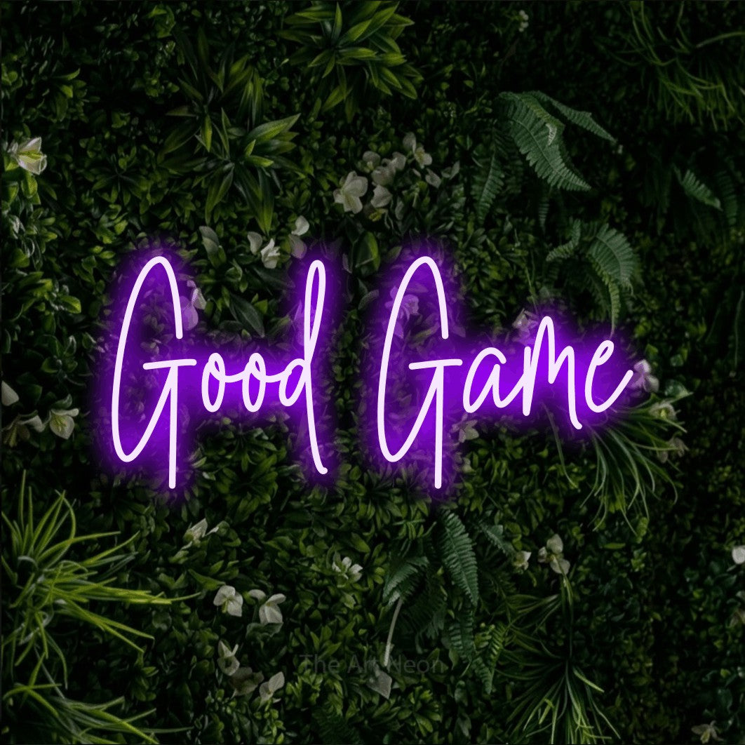 Purple script-style LED neon sign reading "Good Game" against a leafy green wall for gaming room décor