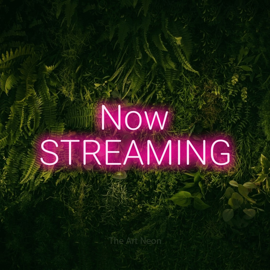 Hot pink LED neon sign reading "Now Streaming" against a moss-covered green wall for gaming room décor