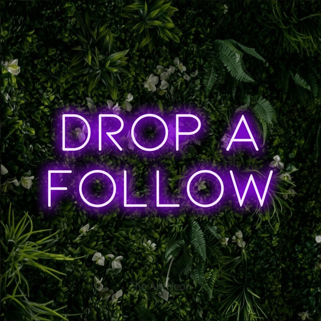 Enseigne néon à DEL à lumière violette, affichant « Drop a Follow » sur un mur de feuillage vert, pour décorer une salle de jeu