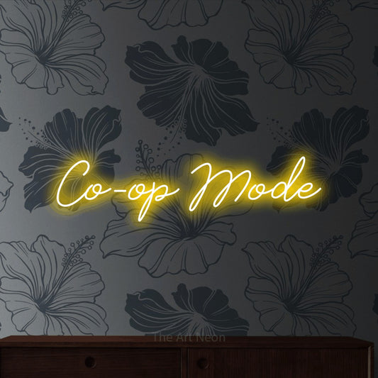 Yellow script-style LED neon sign reading "Co-op Mode" against grey floral wallpaper for gaming room décor