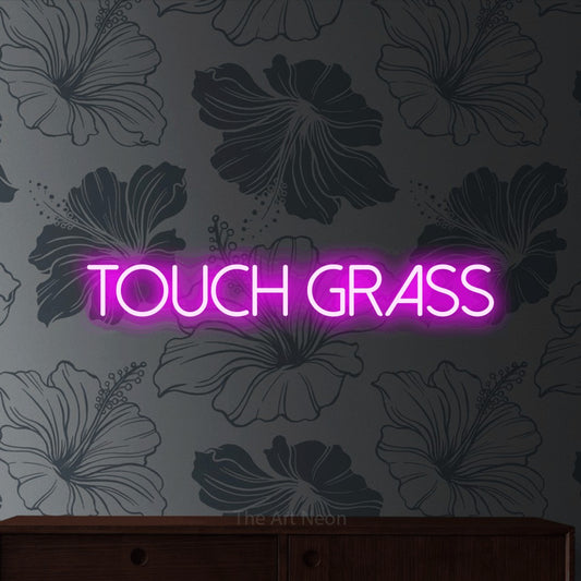 Pink LED neon sign reading "Touch Grass" against grey floral wallpaper for gaming room décor