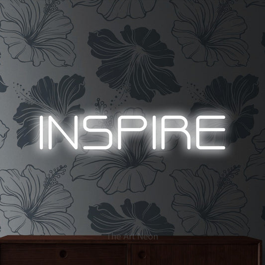 Cool white outline-style LED neon sign reading "Inspire" against grey floral wallpaper