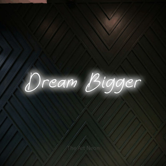 Cool white LED neon sign reading "Dream Bigger" against a dark geometric wood wall