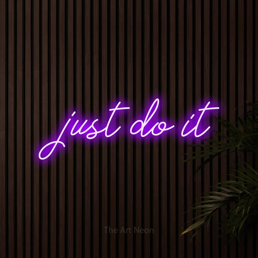 Purple script-style LED neon sign reading "Just Do It" against dark wooden slats