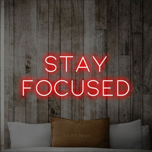 Red LED neon sign reading "Stay Focused" against a whitewashed wooden wall