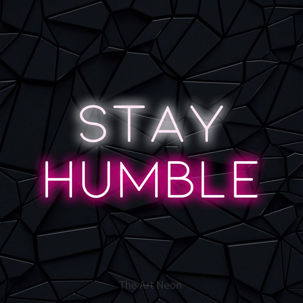 Hot pink and cool white LED neon sign reading "Stay Humble" against a black faceted wall