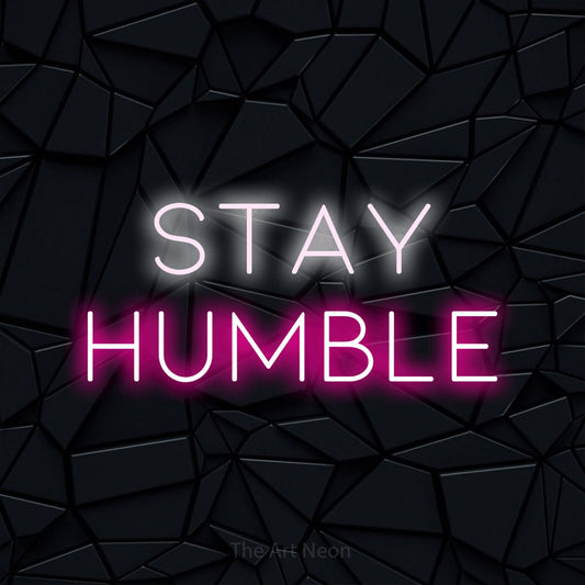 Hot pink and cool white LED neon sign reading "Stay Humble" against a black faceted wall