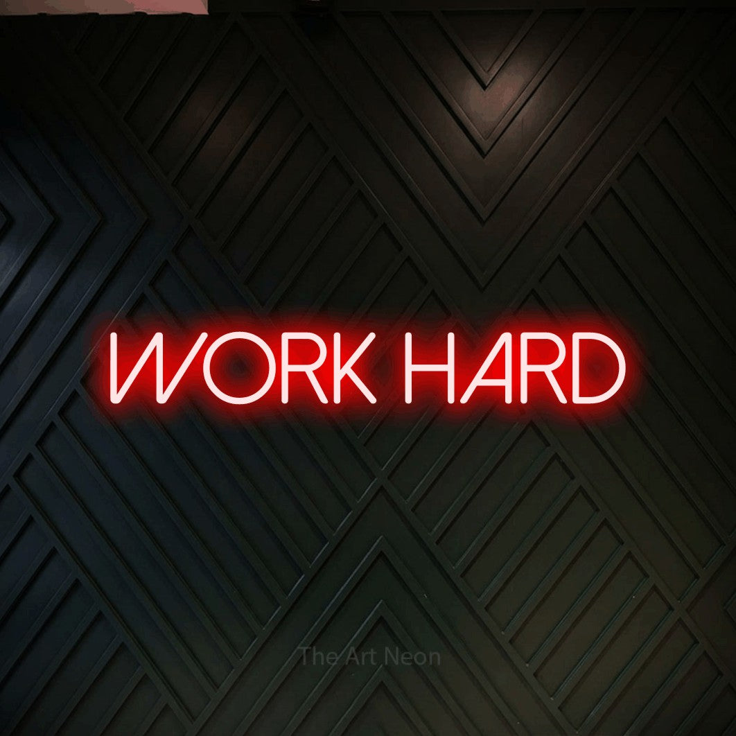 Red LED neon sign reading "Work Hard" against a dark geometric wood wall