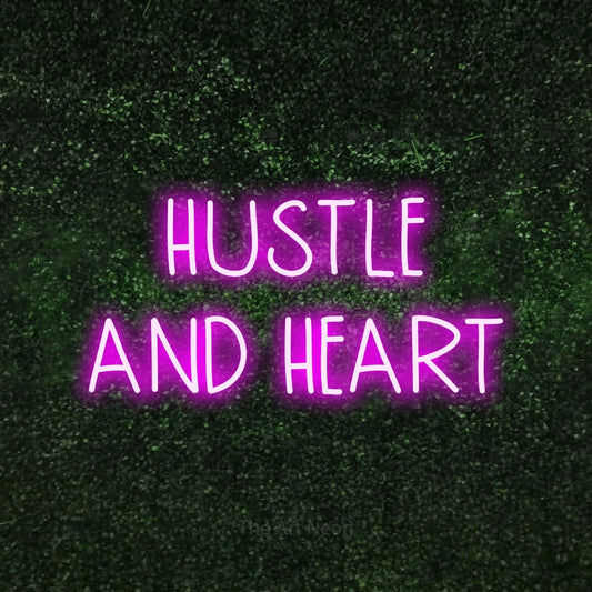 Pink LED neon sign reading "Hustle and Heart" against a textured green moss wall