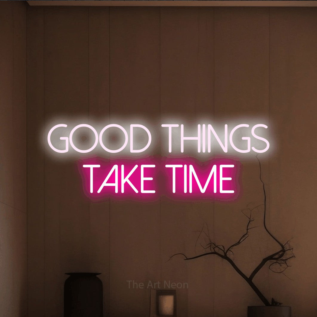 Hot pink and cool white LED neon sign reading "Good Things Take Time" against a warm brown wall