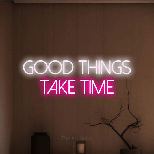 Hot pink and cool white LED neon sign reading "Good Things Take Time" against a warm brown wall
