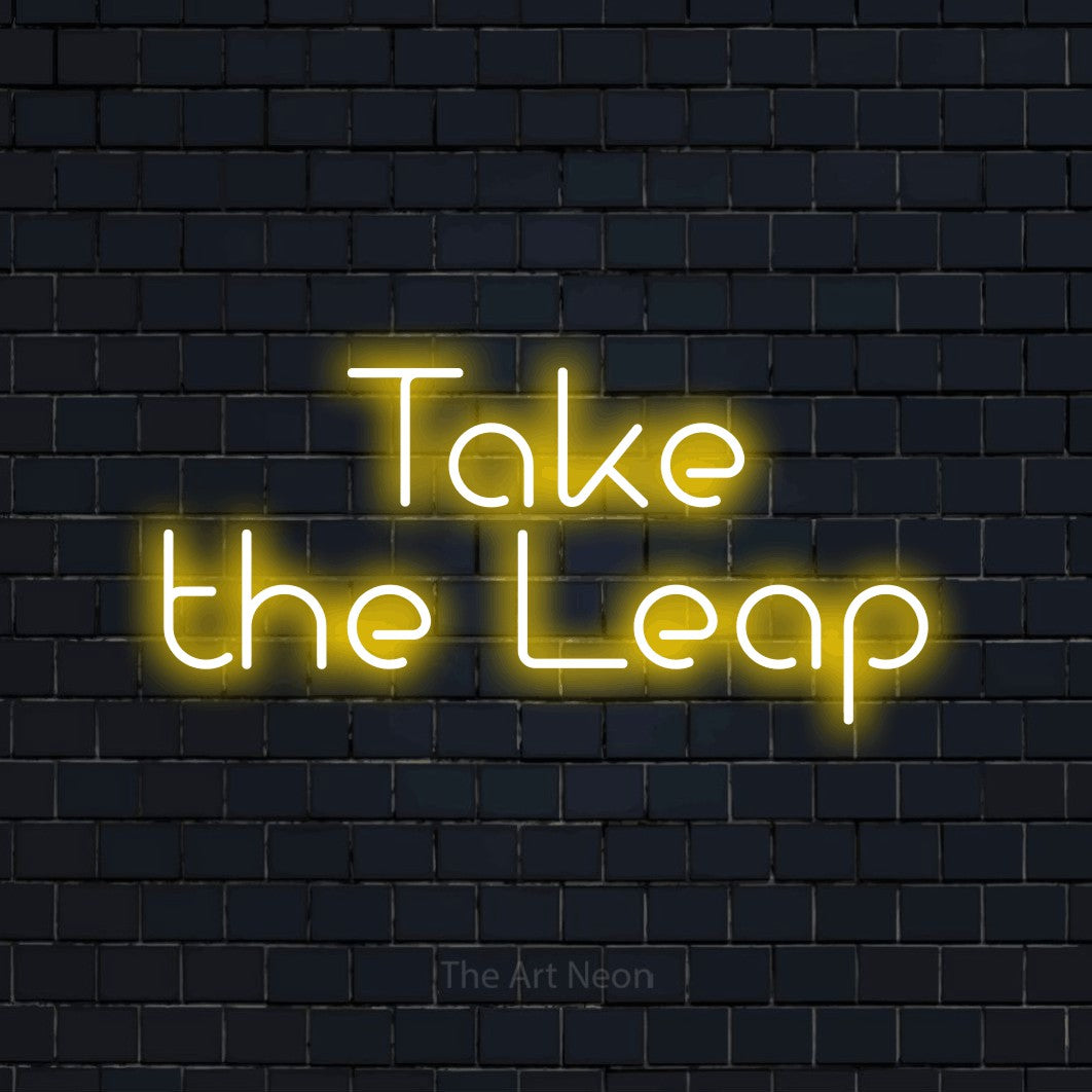 Yellow LED neon sign reading "Take the Leap" against a dark navy brick wall