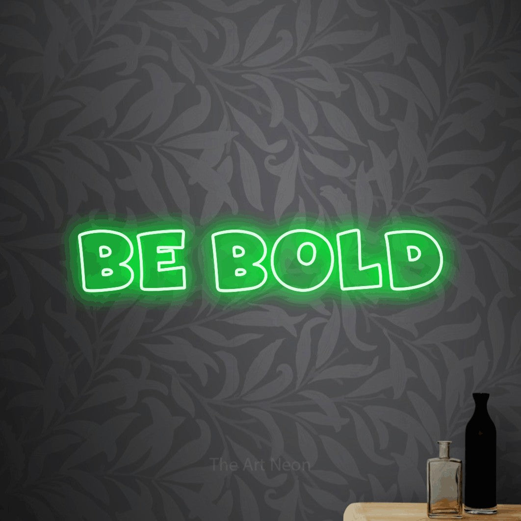 Green outline-style LED neon sign reading "Be Bold" against light grey floral wallpaper