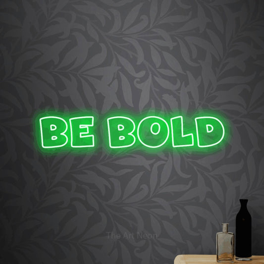 Green outline-style LED neon sign reading "Be Bold" against light grey floral wallpaper
