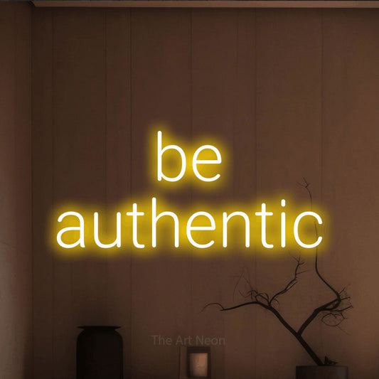 Yellow LED neon sign reading "Be Authentic" against a warm brown wall