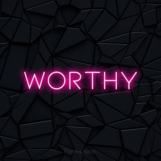 Hot pink LED neon sign reading "Worthy" against a black faceted wall