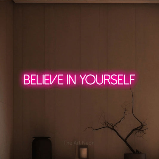 Hot pink LED neon sign reading "Believe in Yourself" against a warm brown wall