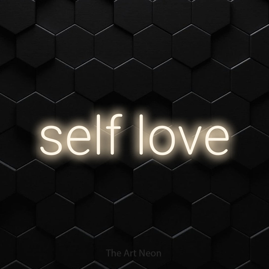 Warm white LED neon sign reading "Self Love" against a black hexagonal wall