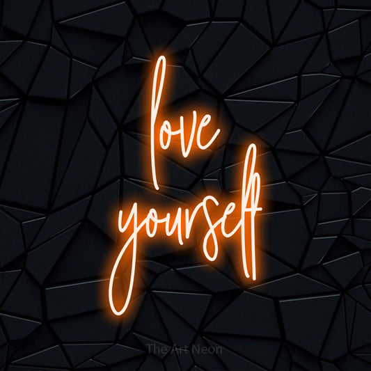 Orange script-style LED neon sign reading "Love Yourself" against a black faceted wall